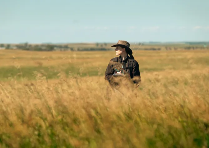 student stands in field while researching monarch butterflies