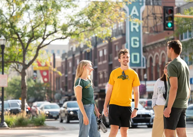 group of students standing downtown in front of Fargo Theatre sign