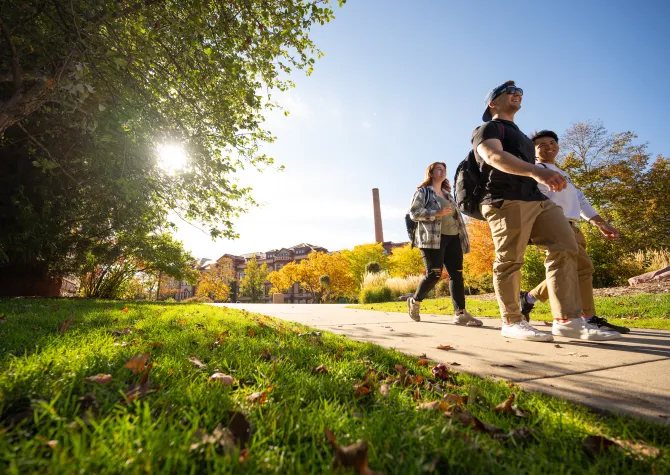 Students walking outside on campus on a sunny day. 