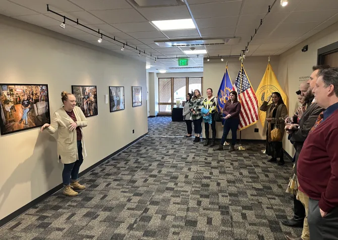 Maria Brien stands in front of photographs in the President's Gallery 