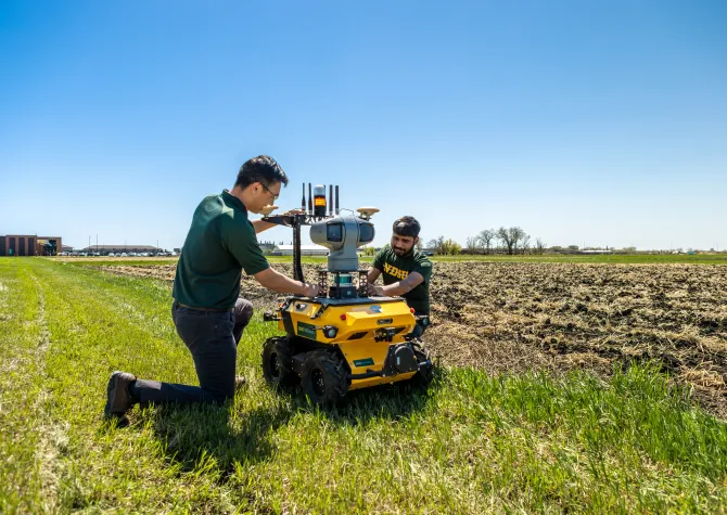 Two people working with precision agriculture equipment in field