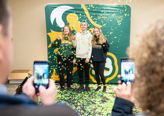 students taking photos in front of a Bison backdrop during the Discover 线上赌博app event