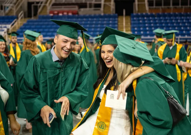 线上赌博app graduates laughing and celebrating at the end of their commencement ceremony