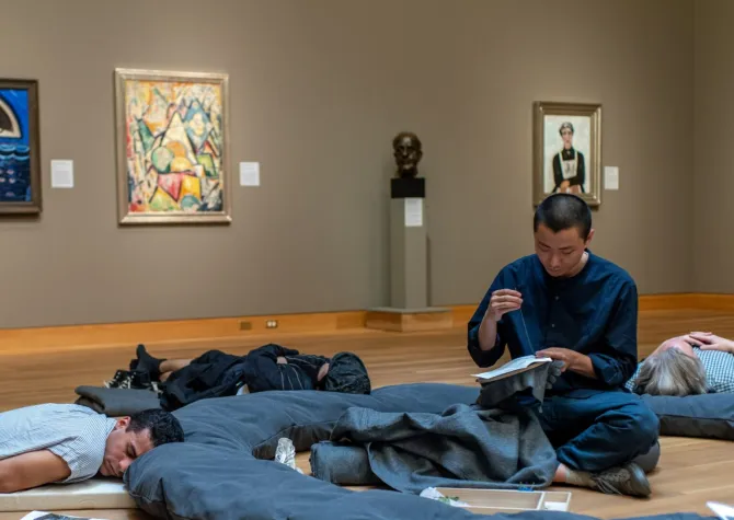 Artist in gallery while people sleeping around him
