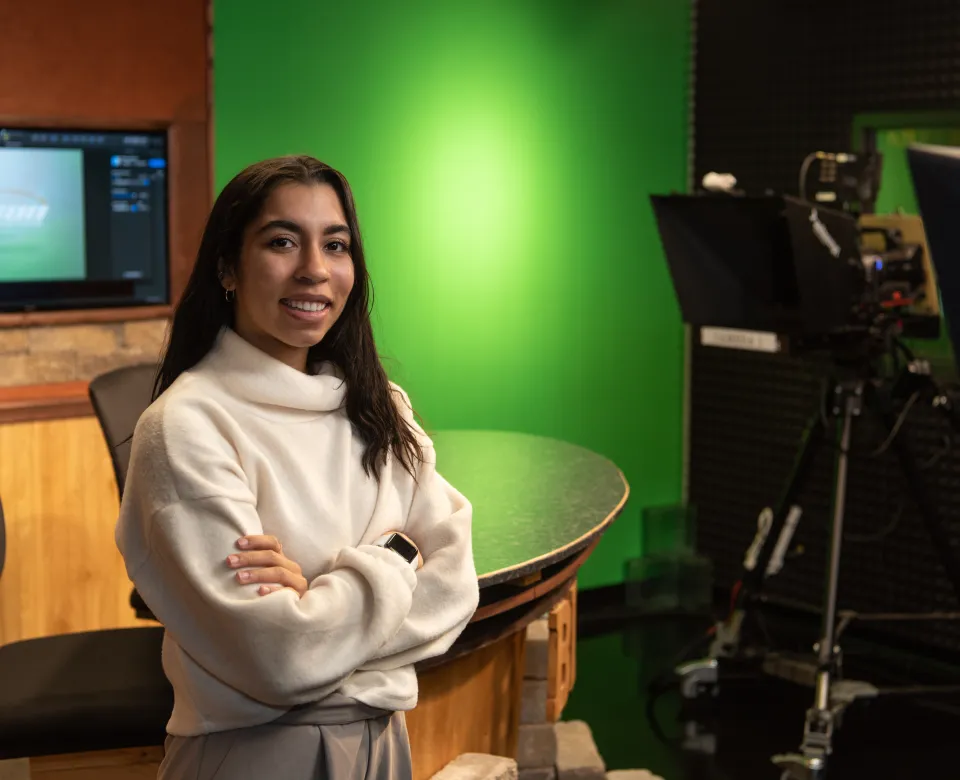 Student standing with arms crossed looking confidently into the camera