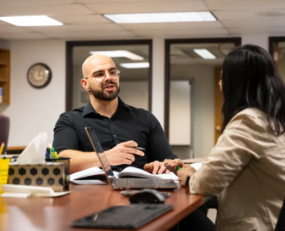 Two graduate students working together at a table.