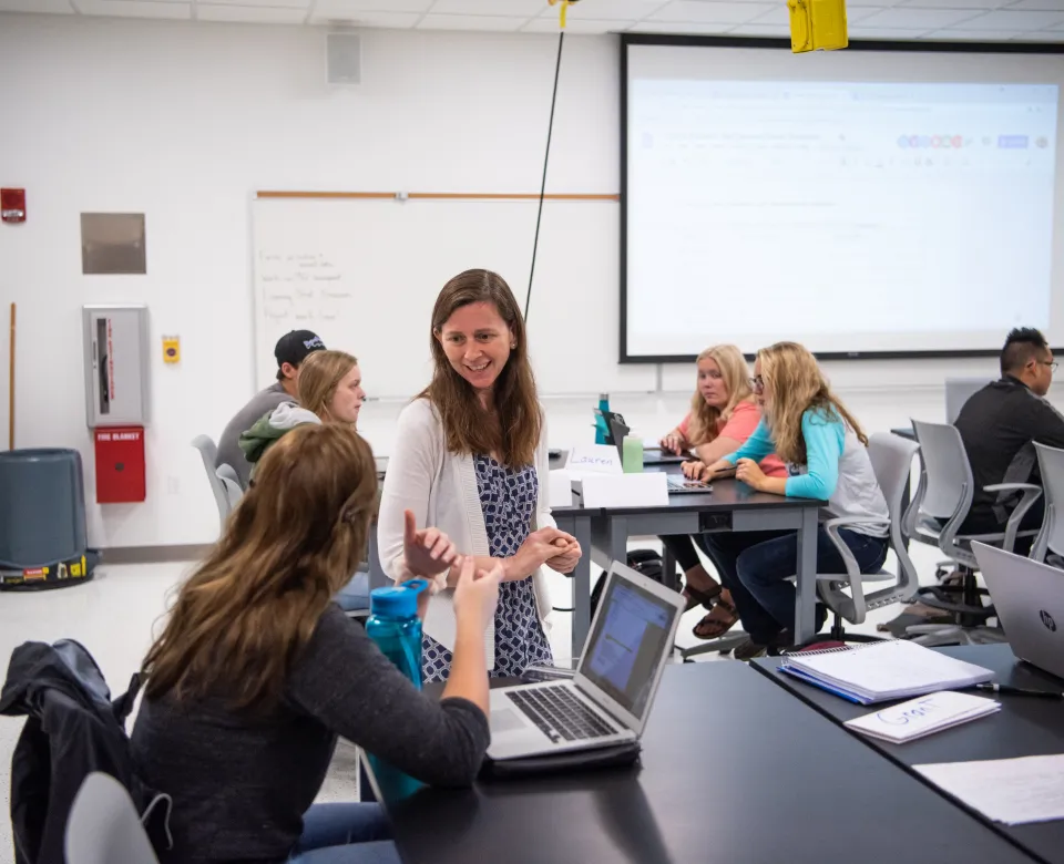 Dr. Momsen talking with student in a classroom setting. 