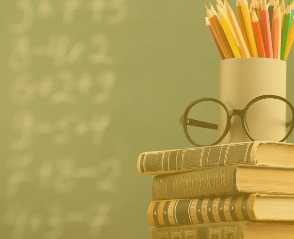 Stack of books with glasses and pencil cup on an educator's desk
