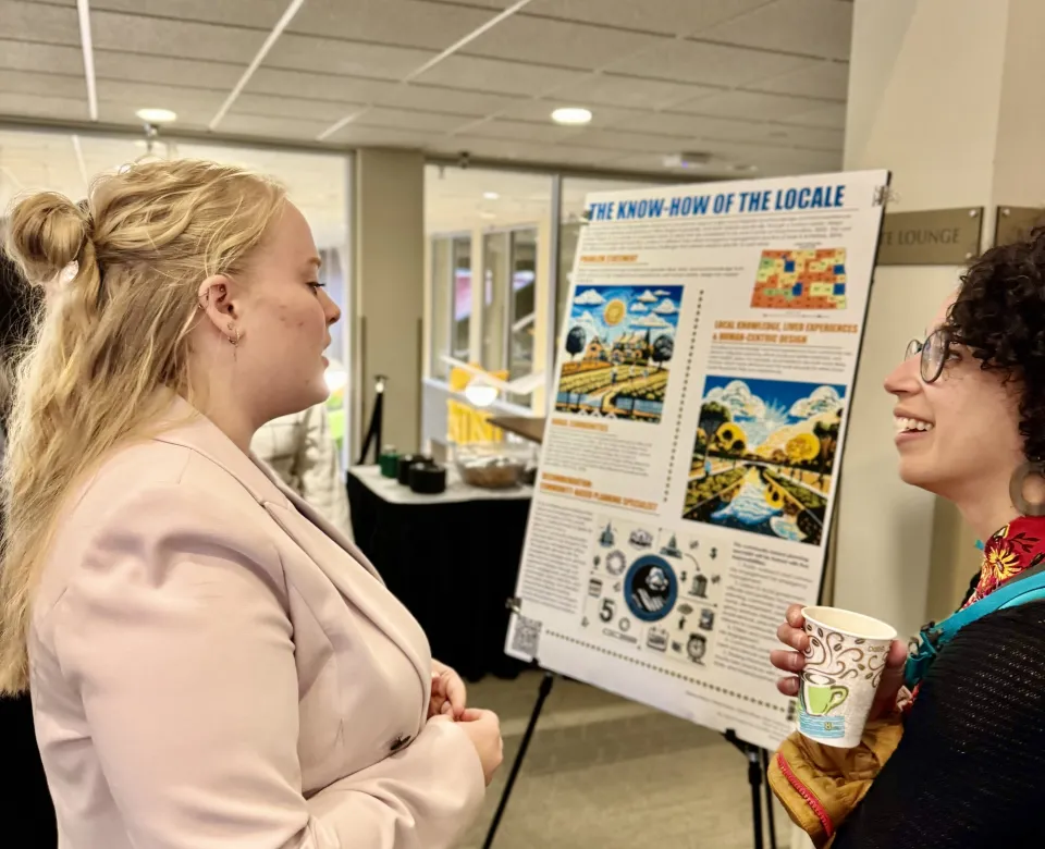 Student sharing information about research project displayed on research poster.