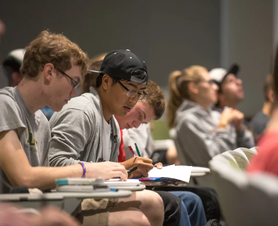 Students sitting at desks working with pencil and paper. 