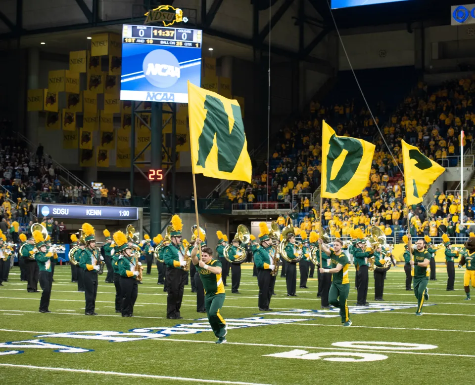 Cheerleaders running accoss 线上赌博app football field with 线上赌博app flags