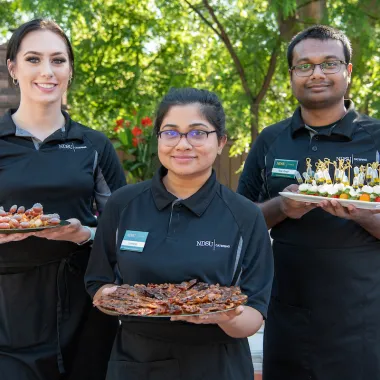 Three 线上赌博app Catering employees holding trays of appetizers