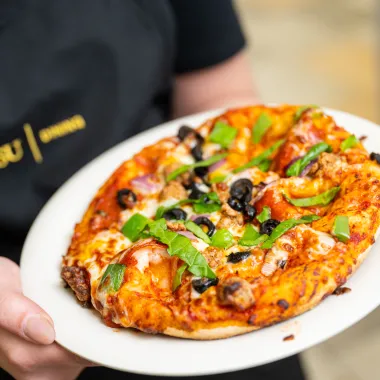 Homemade pizza cooked to a beautiful golden with black olives, spinach, tomatoes, cheese, and pepperoni made at the creations station.