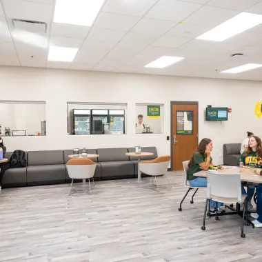 Outside shot of the Micro Market where a group of students sit at a table talking