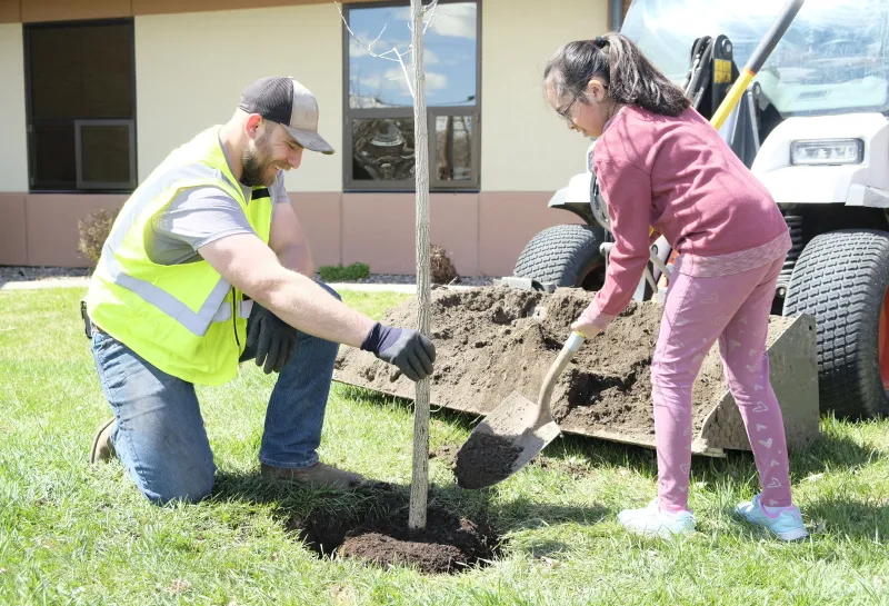 A man and a young girl plant a tree