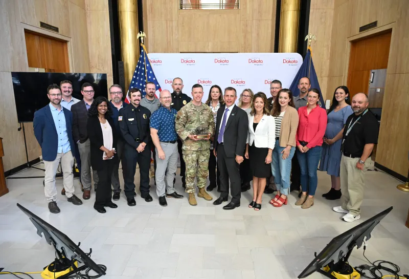 A group of people smile while holding an award