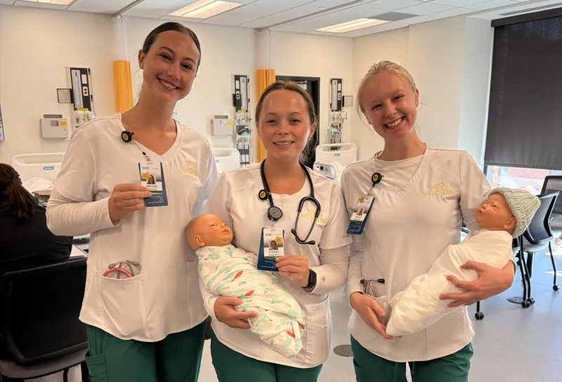 3 nursing students holding sim babies