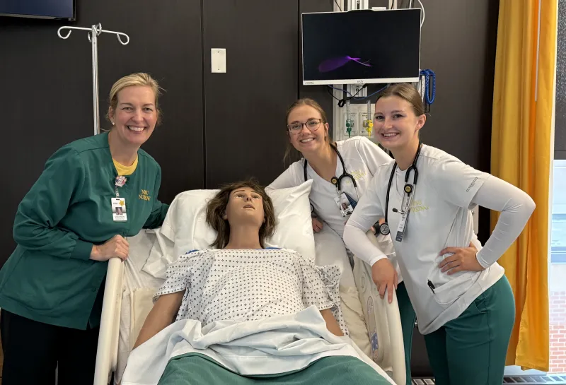 Faculty with simulation doll in hospital bed