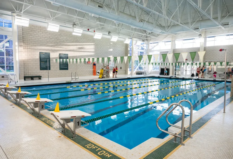 lap pool with green and yellow lane dividers and lifeguards standing by pool in red shirts