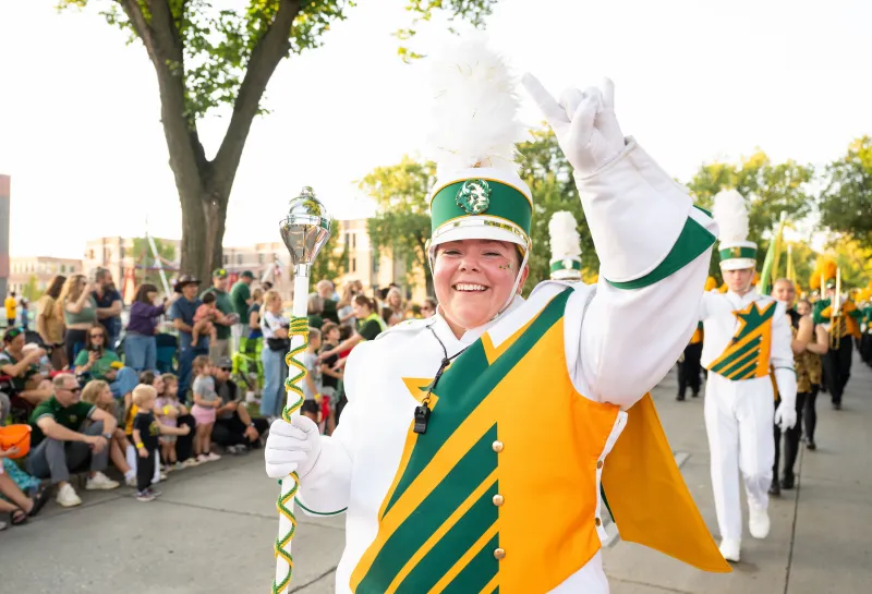 Gold Star Band member flashes Bison horns as she participates in the Homecoming 2025 parade