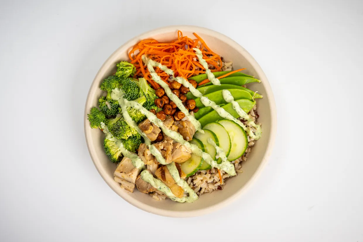 fresh gain bowl featuring whole grains, vegetable, grilled chicken with an avocado dressing