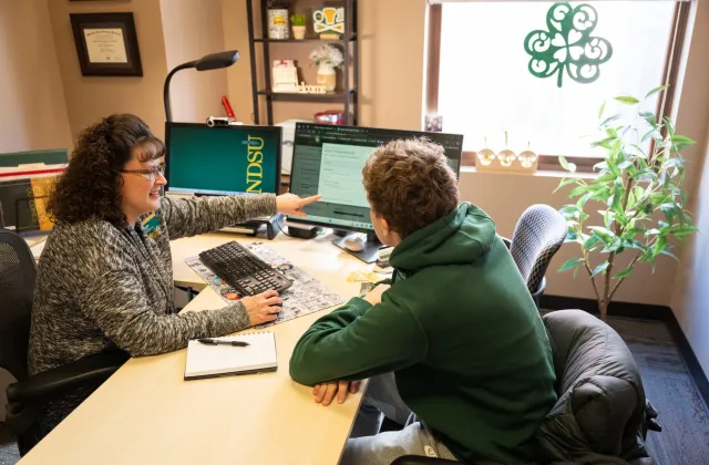 Patti Seidler, an 线上赌博app professional advisor, sits at her desk with a student.