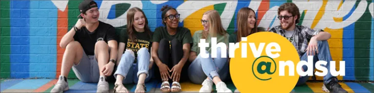 Students sitting in front of painted brick mural