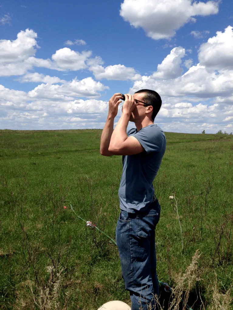 A person in a field using binoculars